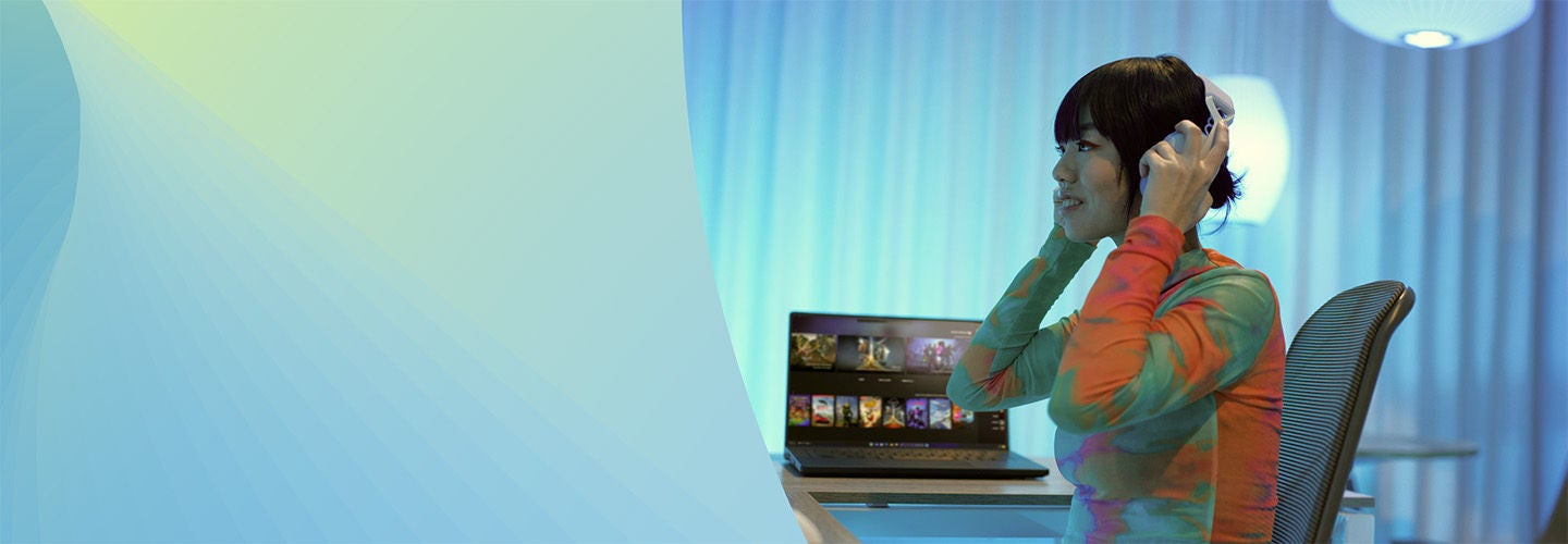 ヘッドフォンをつけてデスクに座って微笑んでいる人。